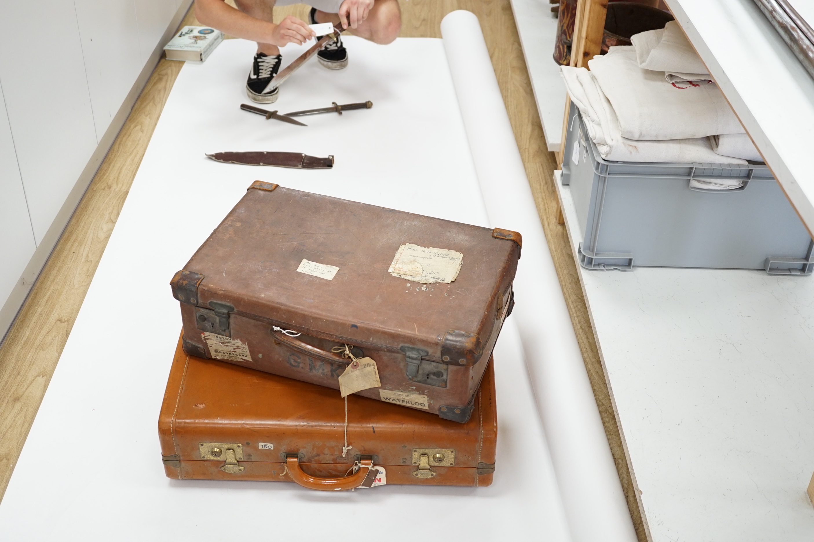 Two vintage suitcases with various labels including British Railways Waterloo, the largest 61cm wide